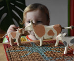 Child playing with Ostheimer wooden toy brown cow and calf figures.