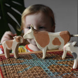 Child playing with Ostheimer wooden toy brown cow and calf figures.