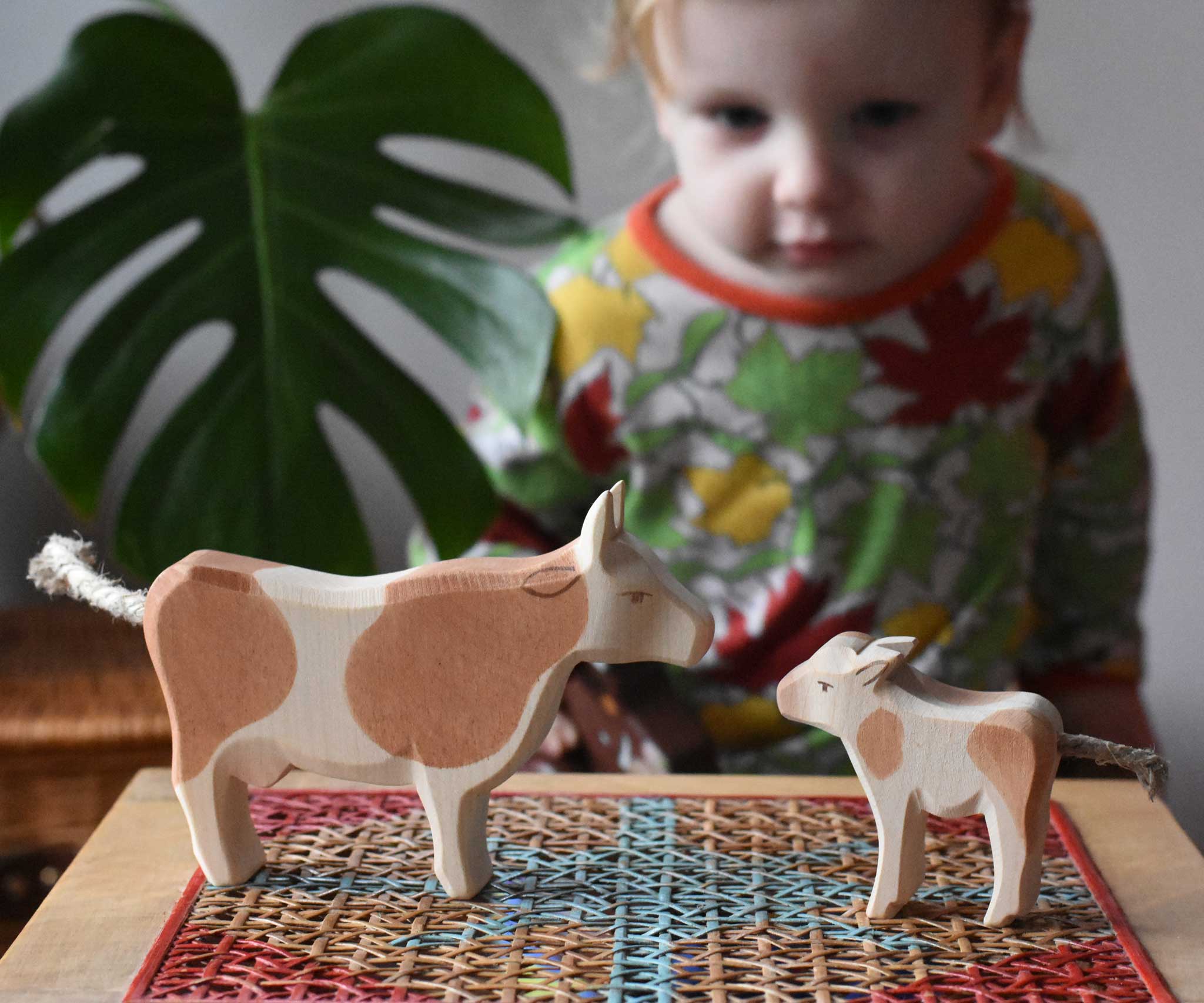 Child playing with Ostheimer wooden toy brown cow and calf figures.