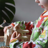 Child holding an Ostheimer brown standing calf in their hand looking down at it with the brown cow in their other hand in the background. 