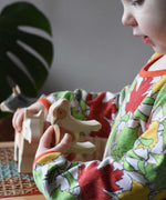 Child holding an Ostheimer brown standing calf in their hand looking down at it with the brown cow in their other hand in the background. 