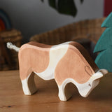 Ostheimer brown and white ox wooden toy figure placed on a wooden surface.