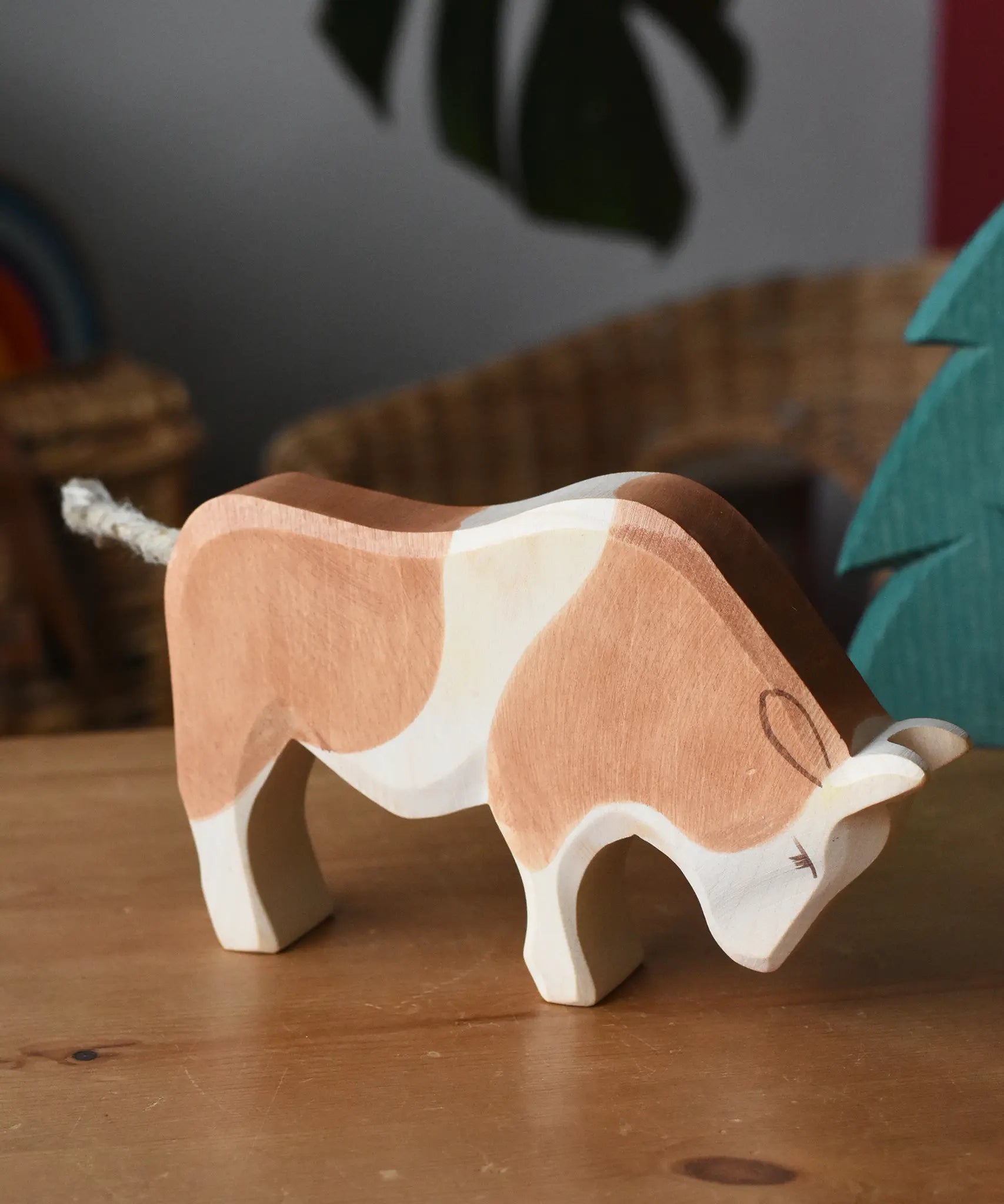 Ostheimer brown and white ox wooden toy figure placed on a wooden surface.