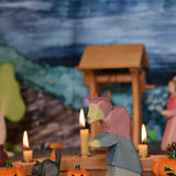 Ostheimer hand made and hand painted wooden witch and cat figures  placed on a wooden surface in a seasonal display. An Ostheimer wooden well can be seen in the background along with other wooden figures and a Grimm's celebration ring. These wooden figures are part of a wide range of expertly hand crafted wooden toys here at Babipur. 