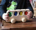 Close up of a child playing with the Ostheimer Natural Bus With 4 People. The child is pushing thew bus along a wooden surface.