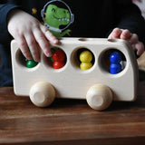 Close up of a child playing with the Ostheimer Natural Bus With 4 People. The child is pushing thew bus along a wooden surface.