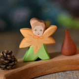 The Ostheimer hand made and hand painted wooden Calendula Flower Child figure toy placed on a Grimm's natural celebration ring. 