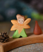 The Ostheimer hand made and hand painted wooden Calendula Flower Child figure toy placed on a Grimm's natural celebration ring. 