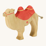 A brown wooden camel figure with a red saddle on a cream background