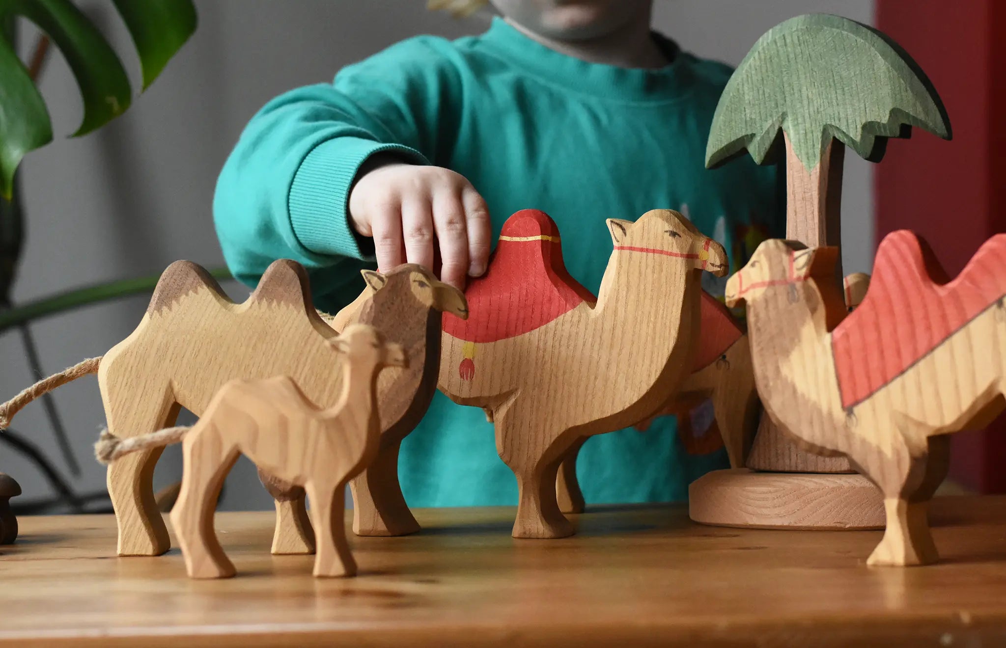 Child playing with a collection of Ostheimer handmade camel wooden toy figures.