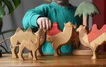 Child playing with a collection of Ostheimer handmade camel wooden toy figures.