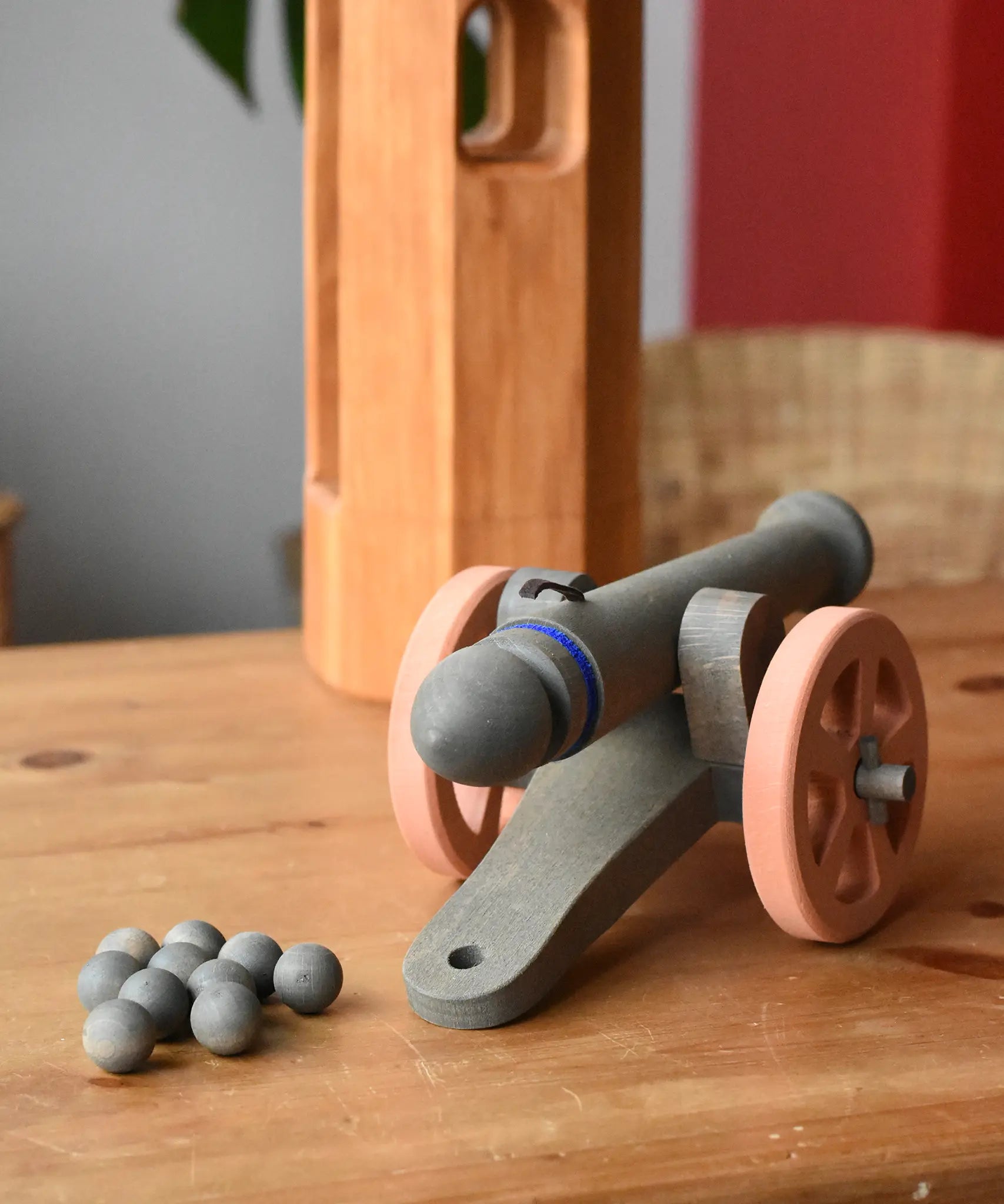 Back of the Ostheimer cannon wooden toy with 10 wooden balls placed on a wooden surface.