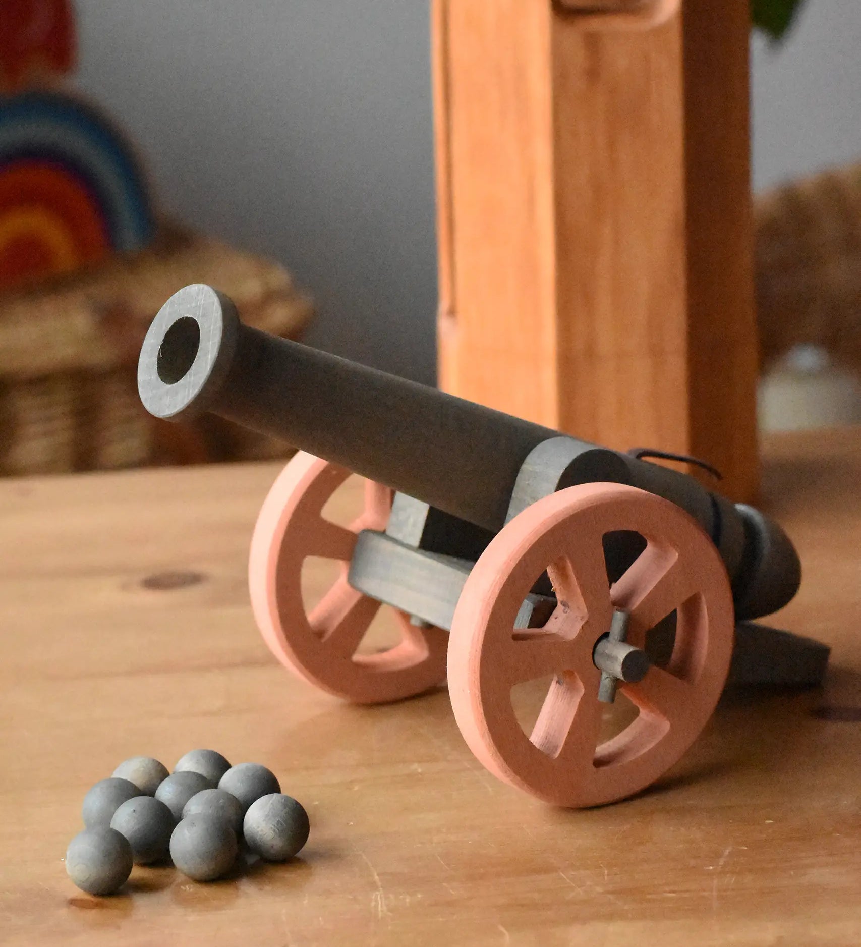 Ostheimer cannon wooden toy with 10 wooden balls placed on a wooden surface.