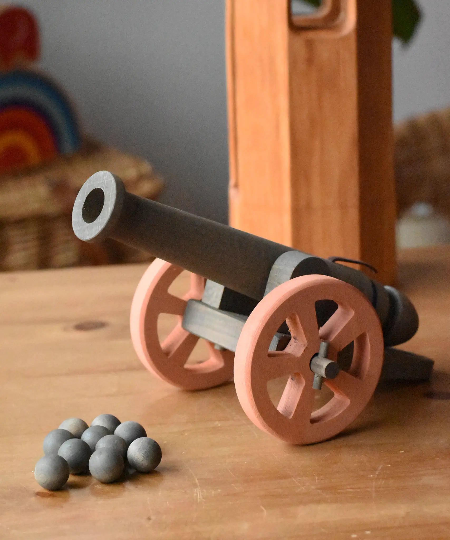 Ostheimer cannon wooden toy with 10 wooden balls placed on a wooden surface.