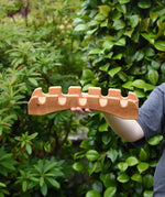 Ostheimer handmade wooden castle bridge toy in a child's hand.