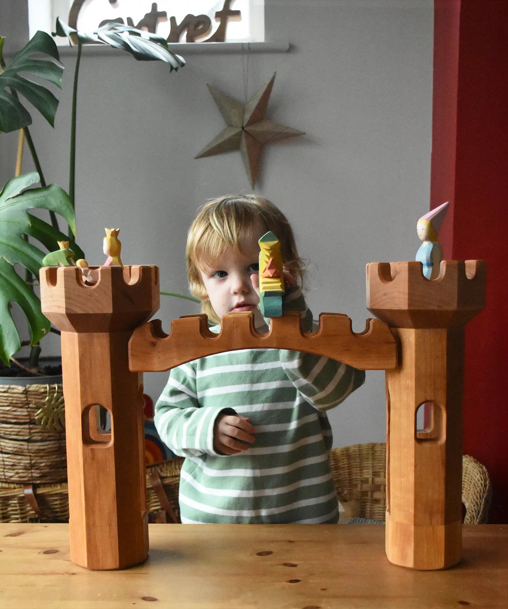 Ostheimer wooden castle bridge toy placed inbetween two round towers with princesses, frog king and dragon figures placed on the towers.