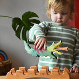 Ostheimer wooden castle bridge toy with a child placing a green dragon on it. 