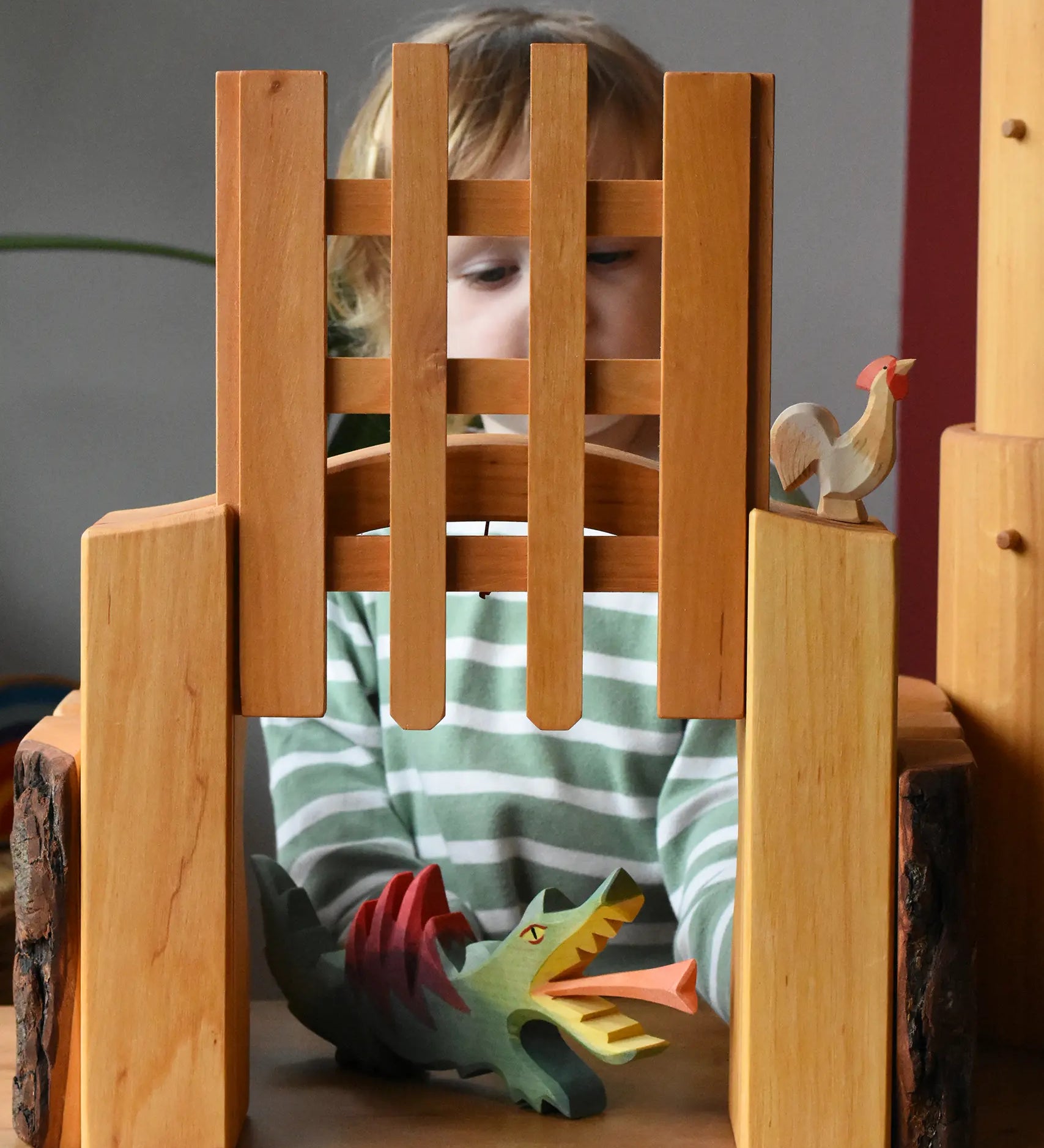 Ostheimer wooden castle trellised gate with a child placing a dragon underneath the open gate.