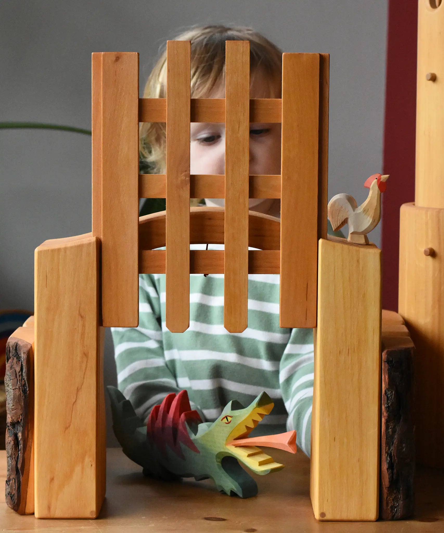 Ostheimer wooden castle trellised gate with a child placing a dragon underneath the open gate.