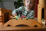 Ostheimer castle and wharf set placed at the front of a small world play set up with a child behind placing a dragon figure on the wharf bridge.