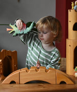 Ostheimer castle and wharf set placed at the front of a small world play set up with a child behind holding a dragon figure.
