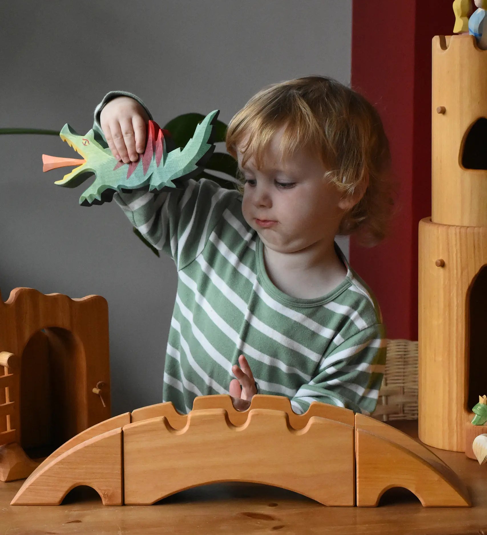 Ostheimer castle and wharf set placed at the front of a small world play set up with a child behind holding a dragon figure.