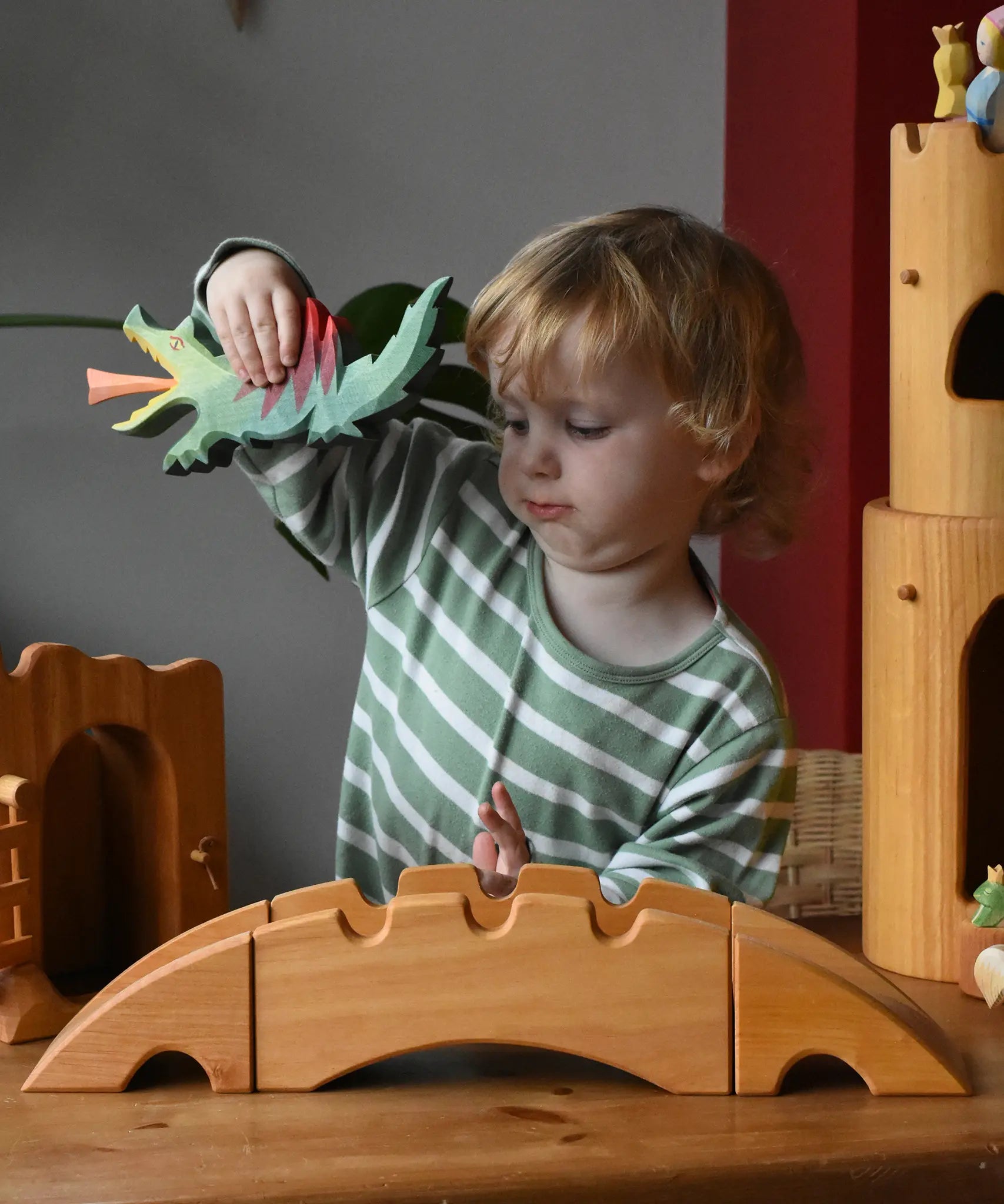 Ostheimer castle and wharf set placed at the front of a small world play set up with a child behind holding a dragon figure.
