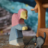 Ostheimer hand made and hand painted wooden witch and cat figures  placed on a wooden surface. An Ostheimer wooden well can be seen in the background. These wooden figures are part of a wide range of expertly hand crafted wooden toys here at Babipur. 