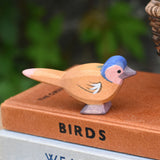 A close up of an Ostheimer wooden chaffinch bird figure placed on a pile of old books.