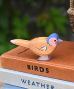 A close up of an Ostheimer wooden chaffinch bird figure placed on a pile of old books.