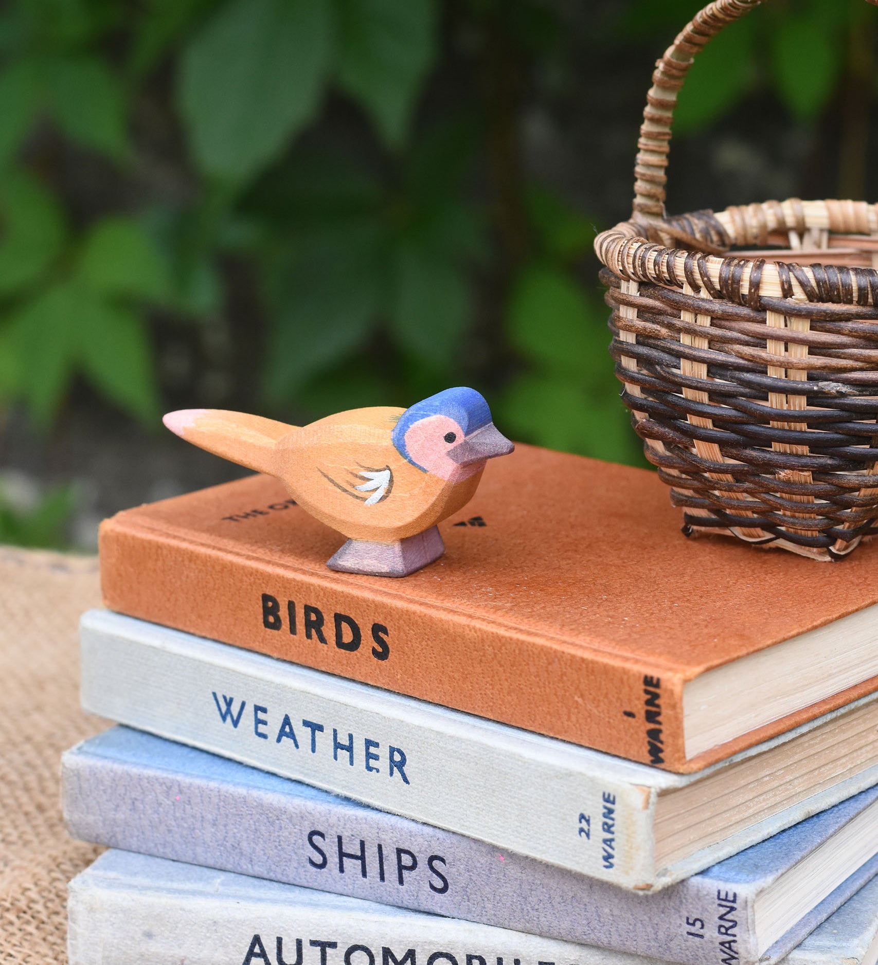 An Ostheimer wooden chaffinch bird figure placed on a pile of old books.