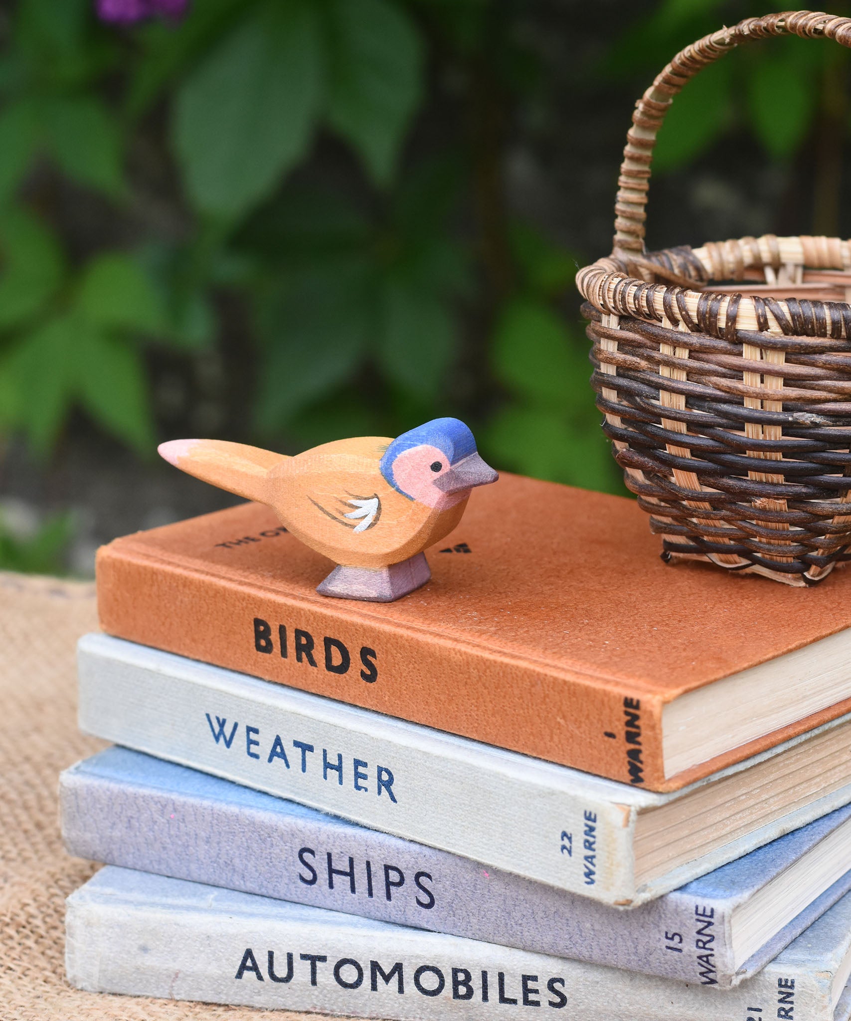 An Ostheimer wooden chaffinch bird figure placed on a pile of old books.