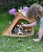 A child placing an Ostheimer drinking calf on a black and white standing cow figure in the Ostheimer cottage. These wooden figures are part of a large range of expertly hand crafted, Waldorf inspired, wooden toys here at Babipur. 