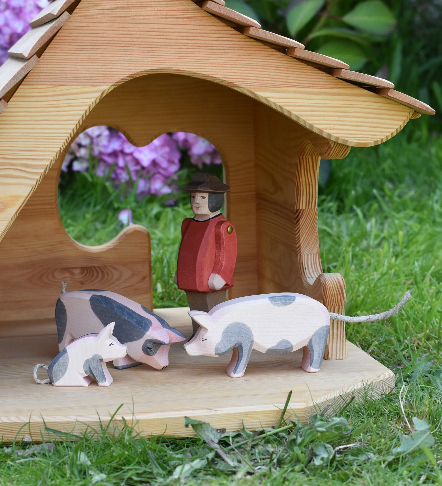 Ostheimer pig figures placed in the Ostheimer wooden cottage with a male farmer figure. These wooden figures are part of a large range of expertly hand crafted, Waldorf inspired, wooden toys here at Babipur. 
