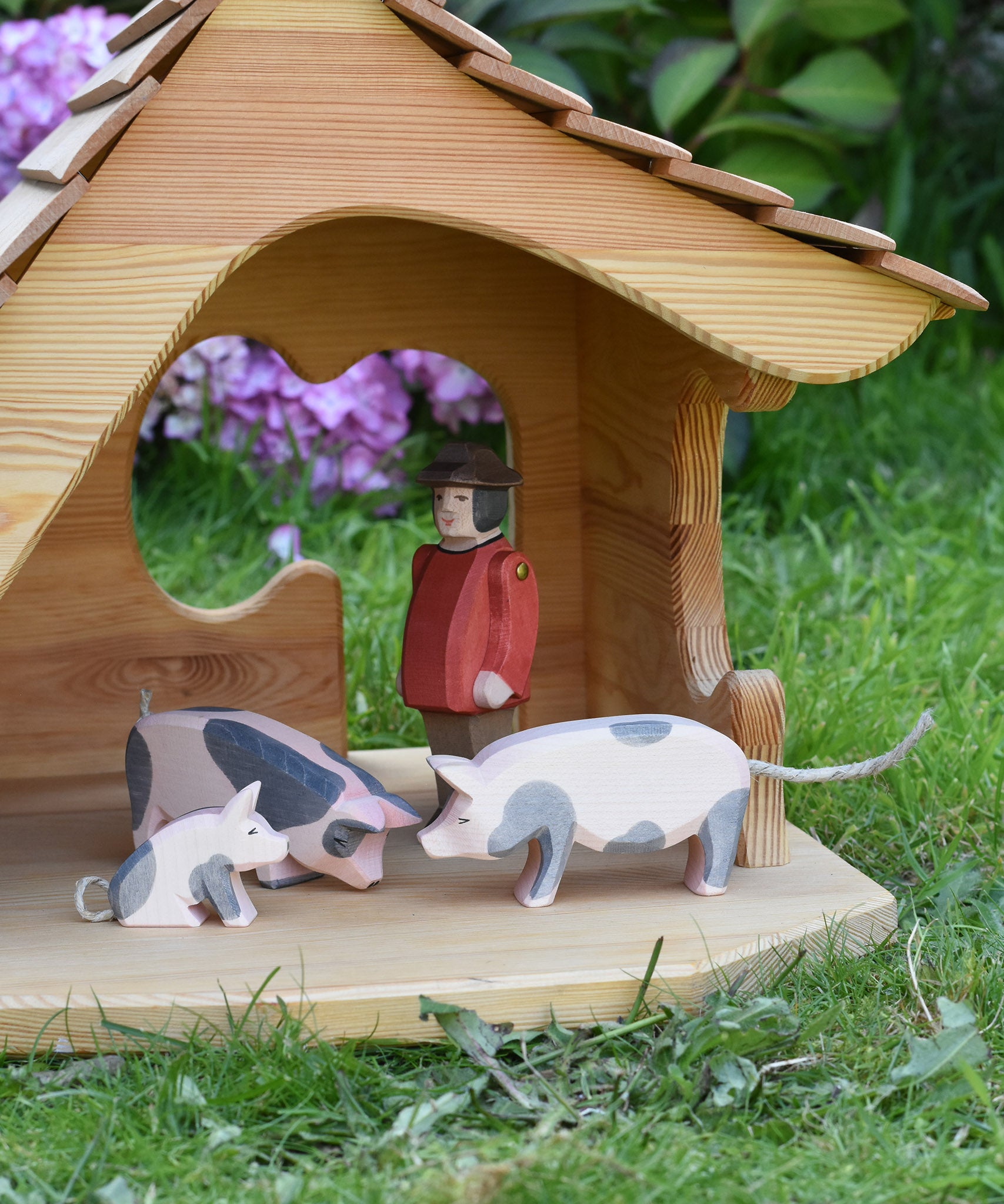 Ostheimer pig figures placed in the Ostheimer wooden cottage with a male farmer figure. These wooden figures are part of a large range of expertly hand crafted, Waldorf inspired, wooden toys here at Babipur. 
