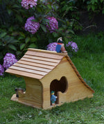 An Ostheimer wooden cottage dolls house with an sitting shepard figure placed on the roof. These wooden figures are part of a large range of expertly hand crafted, Waldorf inspired, wooden toys here at Babipur. 