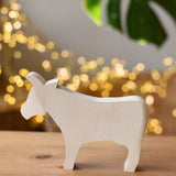 Ostheimer cow paint your own wooden figure placed on a wooden surface. 