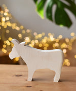 Ostheimer cow paint your own wooden figure placed on a wooden surface. 