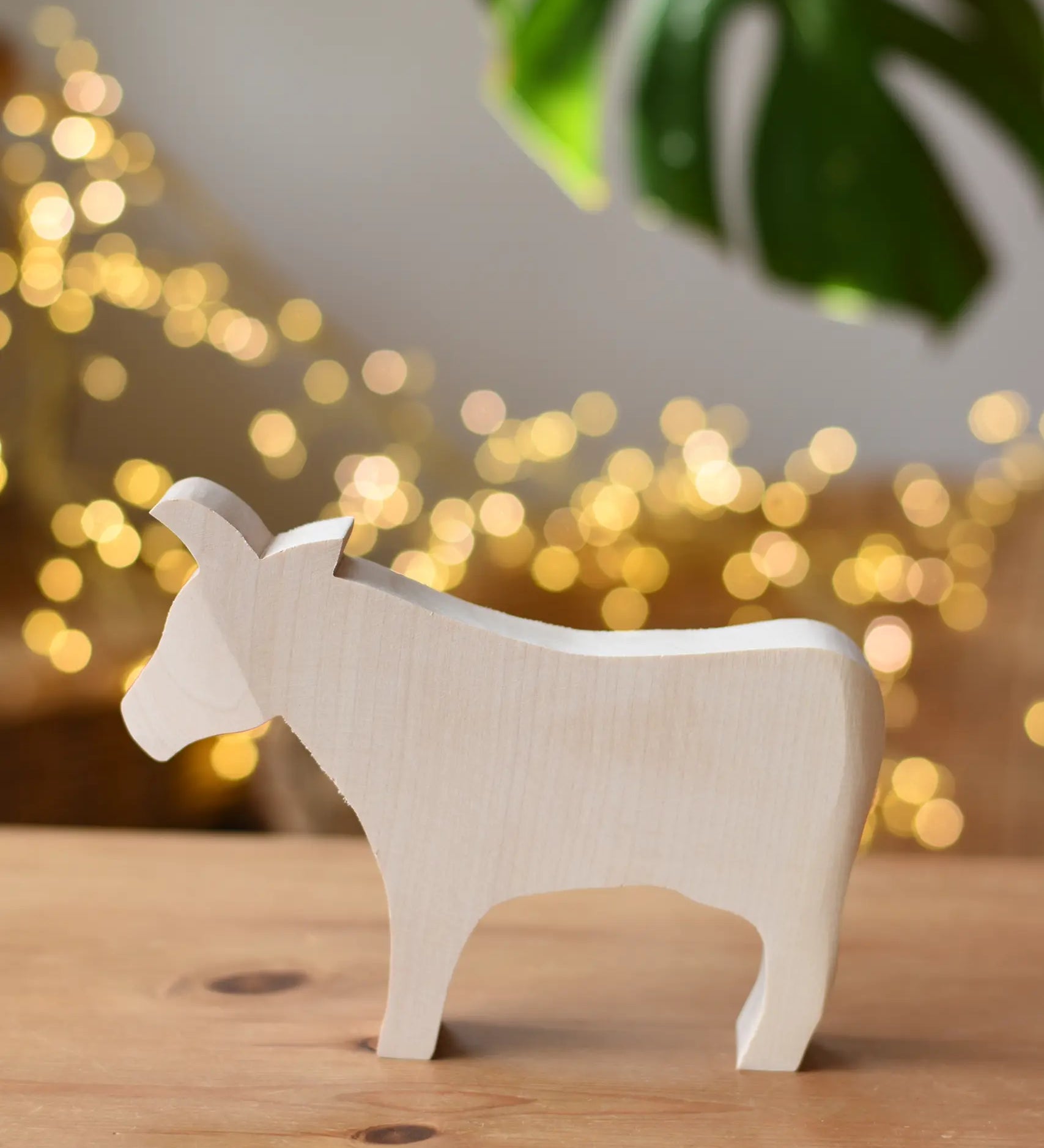 Ostheimer cow paint your own wooden figure placed on a wooden surface. 
