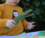 Ostheimer crocodile wooden toy figure in a child's hand with it's mouth open. 
