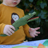 Ostheimer crocodile wooden toy figure in a child's hand with it's mouth open. 