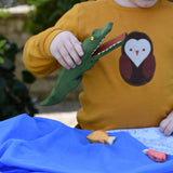Ostheimer crocodile wooden toy figure with moveable jaw in a child's hand with it's mouth open. 
