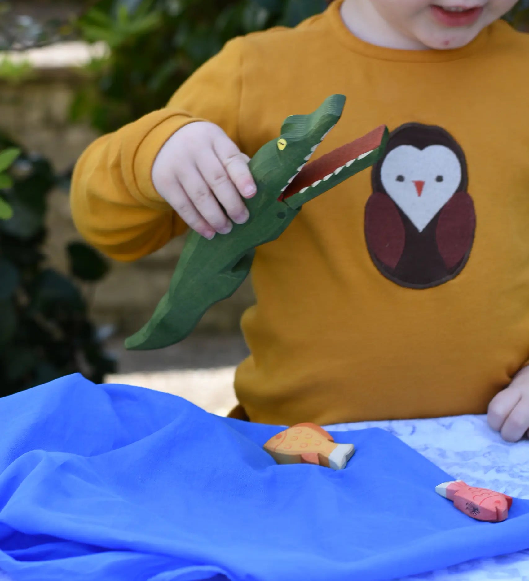 Ostheimer crocodile wooden toy figure with moveable jaw in a child's hand with it's mouth open. 