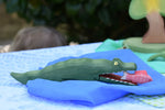 Ostheimer crocodile wooden toy figure on a blue Laura's play cloth. Red fish has been placed in the crocodiles mouth. 