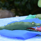 Ostheimer crocodile wooden toy figure on a blue Laura's play cloth. Red fish has been placed in the crocodiles mouth. 