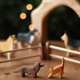  An Ostheimer dachshund and small cat figure placed on a wooden surface in a small world play scene. These wooden figures are part of a wide range of expertly hand crafted wooden toys here at Babipur. 