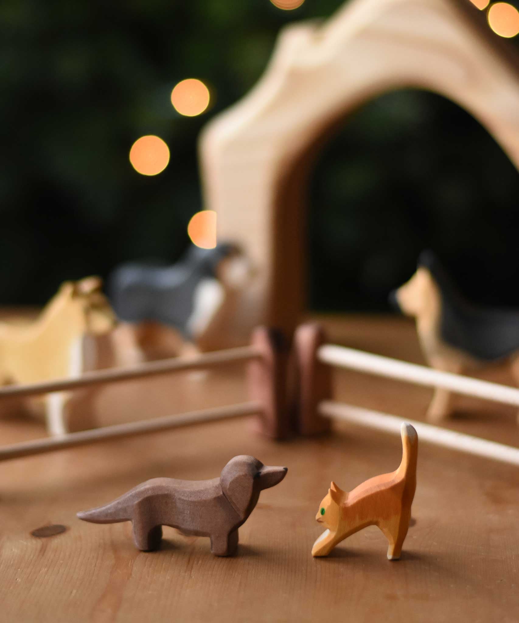  An Ostheimer dachshund and small cat figure placed on a wooden surface in a small world play scene. These wooden figures are part of a wide range of expertly hand crafted wooden toys here at Babipur. 