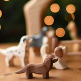 An Ostheimer Dachshund dog wooden toy figure placed at the front of a small world play scene with other dog figures in the background.  These wooden figures are part of a wide range of expertly hand crafted wooden toys here at Babipur. 