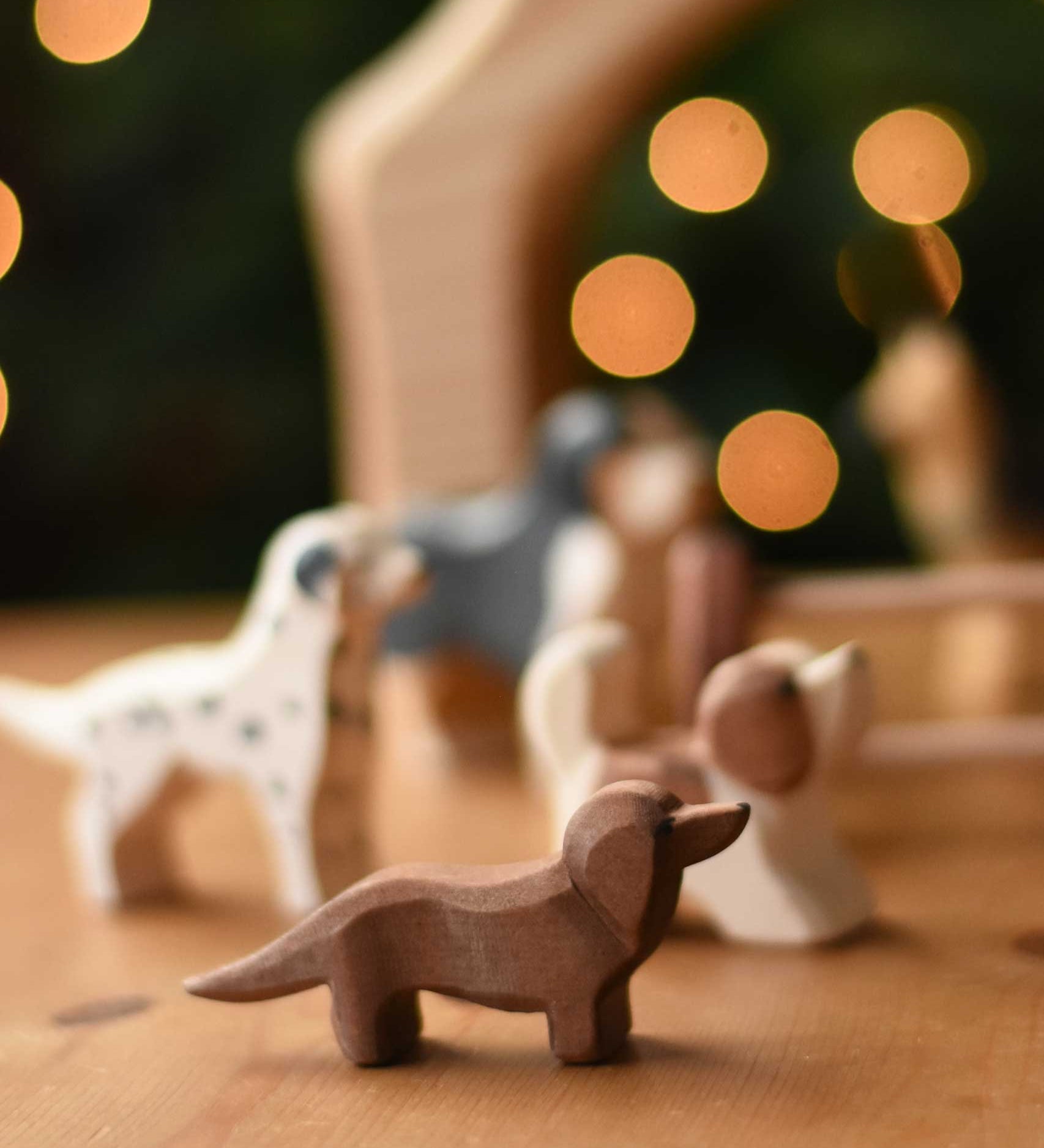An Ostheimer Dachshund dog wooden toy figure placed at the front of a small world play scene with other dog figures in the background.  These wooden figures are part of a wide range of expertly hand crafted wooden toys here at Babipur. 