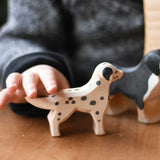 A close up of a child's hand reaching for the Ostheimer dalmatian wooden toy dog figure. These wooden figures are part of a wide range of expertly hand crafted wooden toys here at Babipur. 
